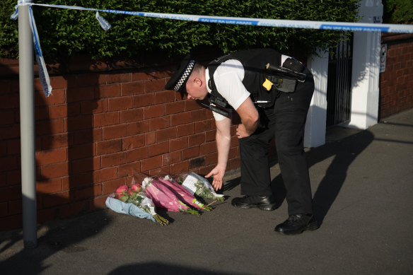 A police officer lays flowers at the scene of the attack where two children were stabbed and 11 others injured.