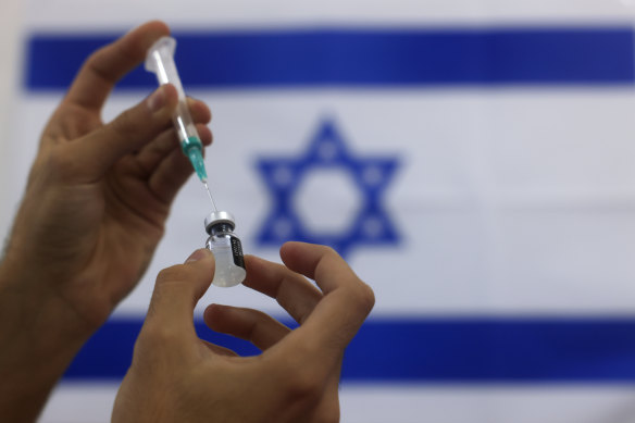 A paramedic prepares a vial of vaccine in Israel.