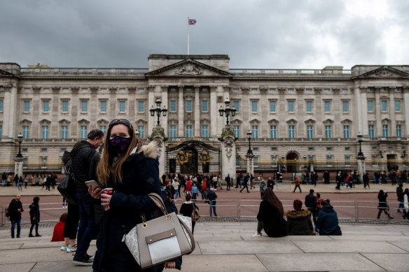 A woman wears a face mask as she visits Buckingham Palace as the outbreak of coronavirus intensifies.