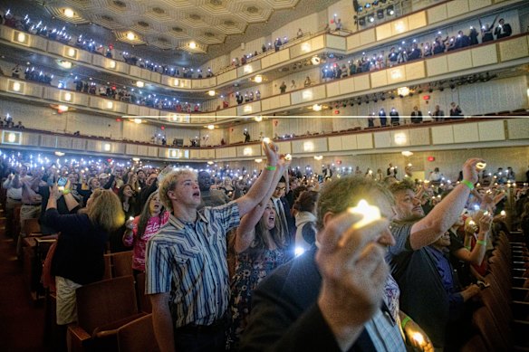 As pessoas seguram velas e cantam durante um memorial e vigília de oração por Charlie Kirk no Kennedy Center, em Washington.