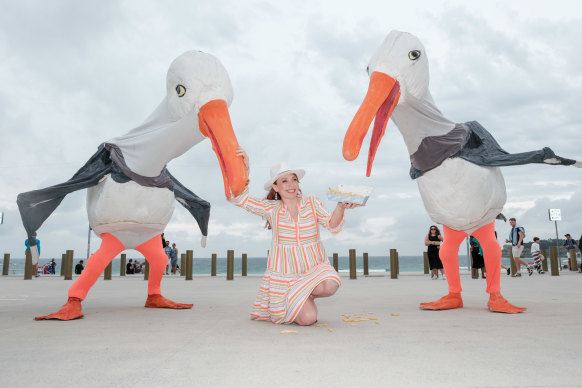Festival director Olivia Ansell surrenders her hot chips to two of the giant seagull puppets that will be roaming around the city over the course of the festival.