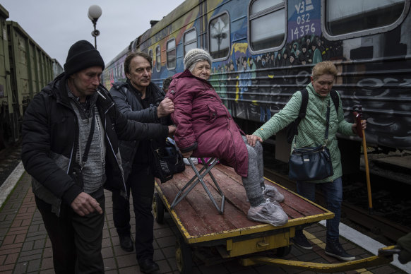 Relatives of Elizaveta, 94, transport her by a cargo cart to the evacuation train in Kherson, Ukraine, on December 1.