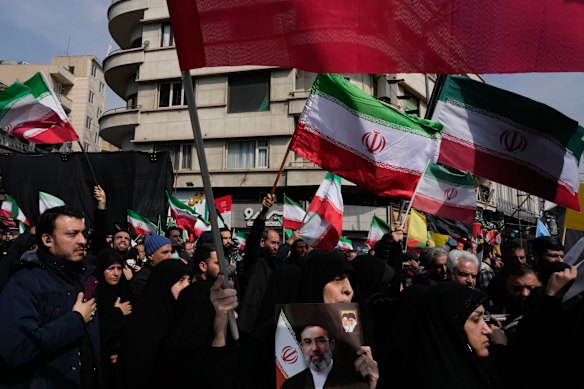 Pessoas em luto agitam bandeiras iranianas durante o cortejo fúnebre de altos oficiais militares iranianos e civis mortos durante a campanha EUA-Israel.