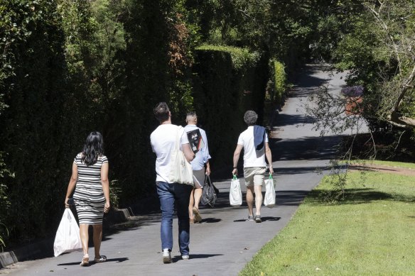 Staff of former premier Dominic Perrottet walk down the private road to his house for a barbecue in Beecroft.