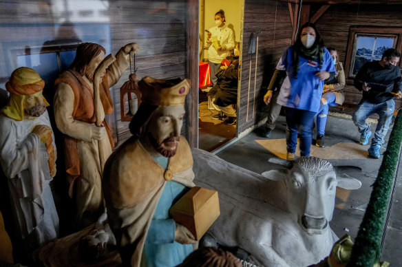 A medical worker and people waiting for a COVID-19 vaccination at a temporary facility next to a Nativity scene at the Christmas market in Offenbach, Germany.