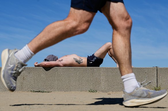 A jogger runs past as a man sunbathes at Crissy Field in San Francisco.