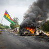 A Kanak flag waving next to a burning vehicle at a roadblock at La Tamoa, in the commune of Paita in New Caledonia.