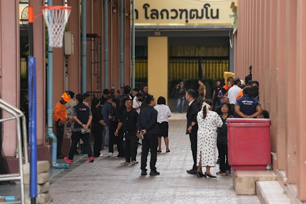 First responders and others stand inside after a shooting at the Debsirin Nonthaburi School in Thailand’s Nonthaburi province, Friday, Aug. 7, 2026. (AP Photo/Sakchai Lalit)