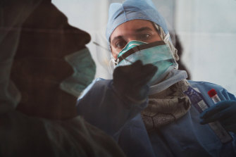 A technician takes a nasal swab for a new coronavirus detection test at a drive-thru testing facility in Abu Dhabi, United Arab Emirates.