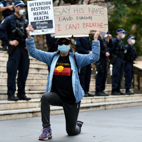 A protester takes the kneel in front of police during a "Free The Refugees" rally at Sydney Town Hall in Sydney.
