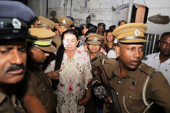 Prison officers escort Shiranthi Rajapaksa to a prison vehicle.