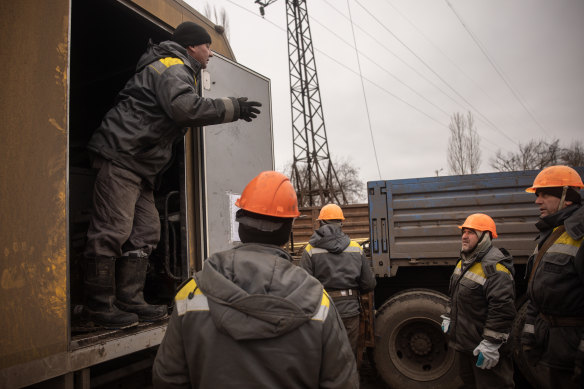 Electricity workers from a team brought in from Odessa and wearing bulletproof vests and helmets prepare to start work to repair a destroyed high voltage power line in Kherson on December 1.