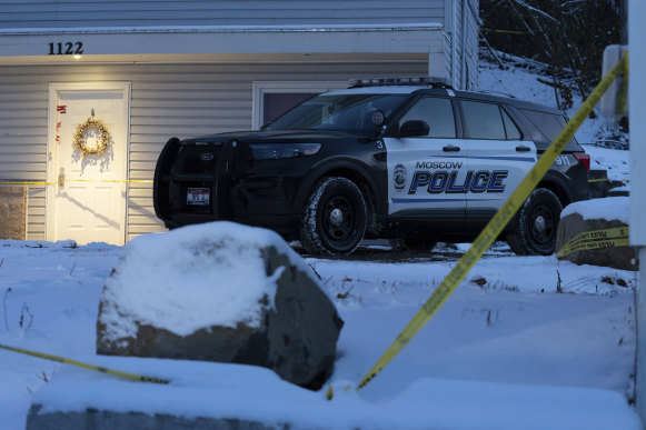 A Moscow police officer stands guard in his vehicle at the home where four University of Idaho students were found dead.