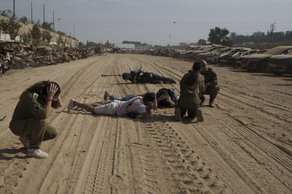 Israeli soldiers and journalists take cover as a siren warns of incoming rockets fired from the Gaza Strip.