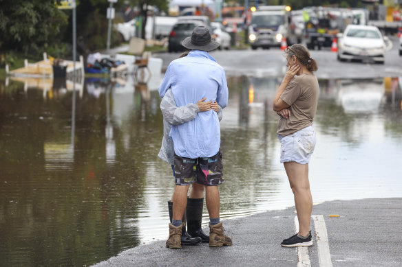 People hug while watching the floodwaters at Eagle Terrace, Auchenflower.
