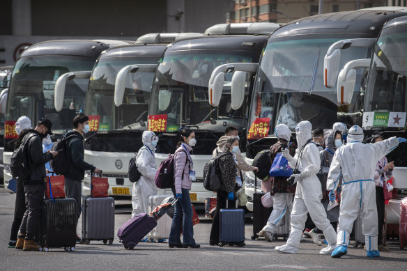 Chinese health officials in protective suits process Wuhan travellers going into 14-day quarantine on arrival in Beijing on Wednesday.