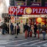 Locals congregate around a 99 Cent Pizzeria in Midtown Manhattan.