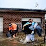 James Larking (right), with the help of Dylan Smith. evacuates his flooded home in Pampoolah.