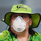 A fan wears a face mask as protection from the smoke at Manuka Oval. 