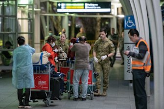 Passengers are assisted at Sydney International Airport before being transported to a hotel for quarantine.