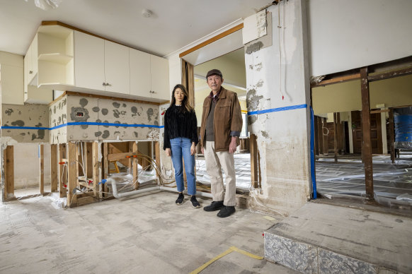 Paul Lau with daughter Stephanie in their flood-damaged Maribyrnong home. The blue line shows where floodwaters rose to in the house, which remains unrepaired.