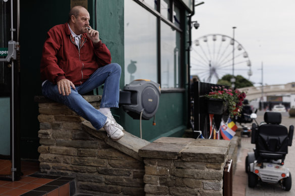     Un uomo è seduto fuori da un pub a Clacton-on-Sea.