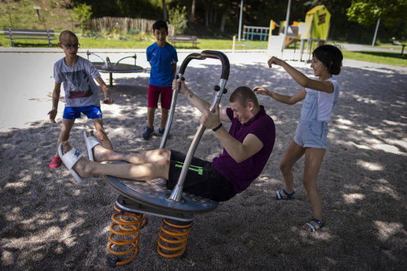 Maksim, left, Eduardo, Timofey, front center, and Varvara, right, play in a park in Loue, western France.