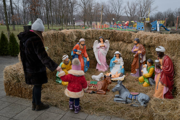 A mother and her child look at a Catholic Christian nativity scene in Pokrovsk, Ukraine.