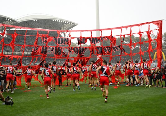 The Adelaide Oval wind tears Essendon’s banner apart.