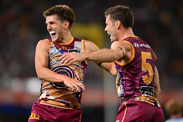 Zac Bailey of the Lions celebrates with Josh Dunkley after kicking a goal.