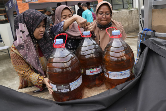 Women load plastic bottles containing bulk cooking oil provided by the government in Indonesia.