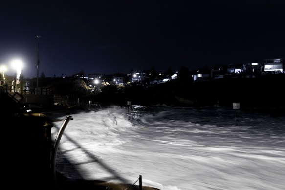 Waves are lit by the lights of the Clovelly Surf Club as a large south- east swell coincides with a high tide on Friday night. 