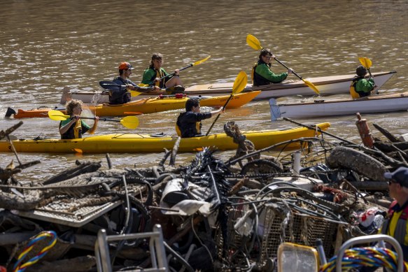 A school group kayaks past a pile of rubbish removed from the Yarra.