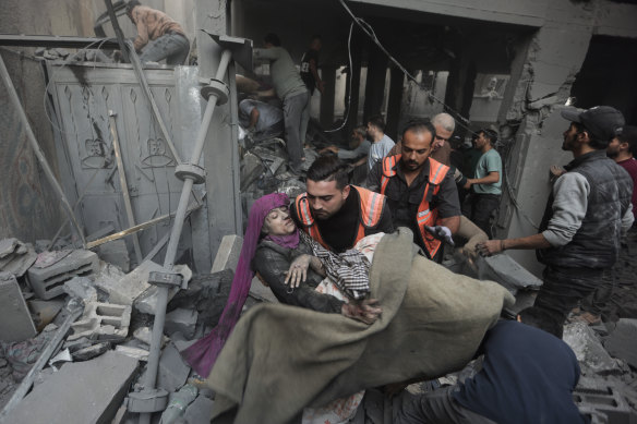 Palestinian rescuers evacuate an injured woman that was found under the rubble of a destroyed house following an Israeli airstrike in Khan Younis refugee camp,.
