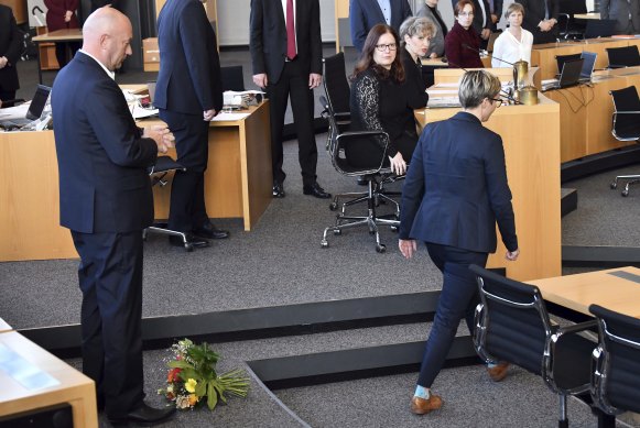 Die Linke's Susanne Hennig-Wellsow, right, walks away from Thomas Kemmerich of the Free Democrats after throwing a bouquet of flowers in front of him in Erfurt, Germany.