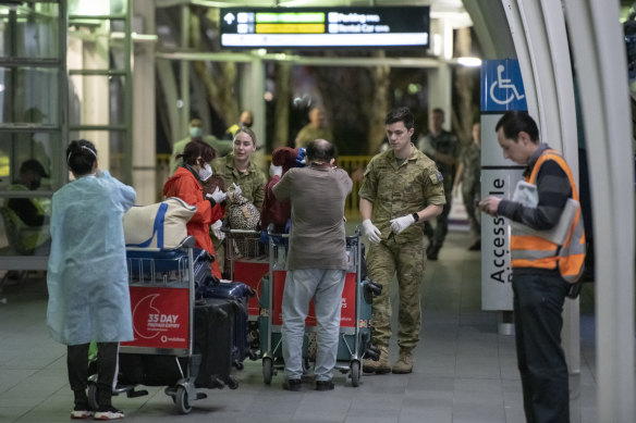 Passengers are assisted at Sydney International Airport before being transported to a hotel for quarantine.