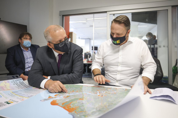 Prime Minister Scott Morrison and Brisbane lord mayor Adrian Schrinner check a map of flooded regions on Monday.