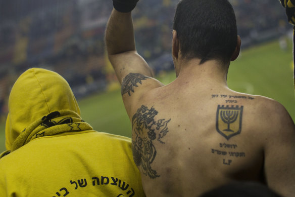 The right tattoo shows the Beitar Jerusalem logo and reads: "I have set watchmen on your walls, Jerusalem; they shall never hold their peace day nor night."