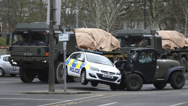 A police car is removed by military personnel from a car park in Salisbury, England. 