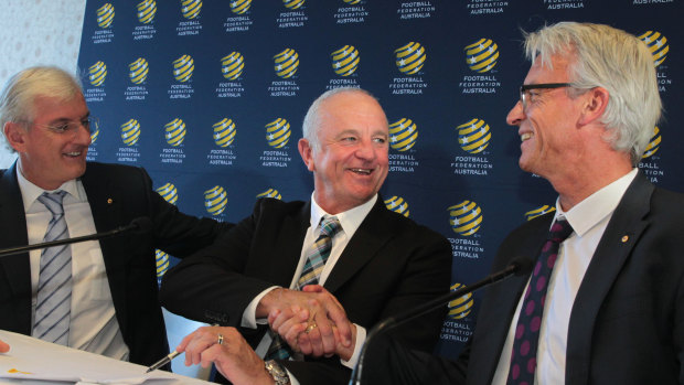 Graham Arnold shakes hands with FFA CEO David Gallop as FFA Chairman Steven Lowy looks on during a press conference to announce Arnold's appointment.