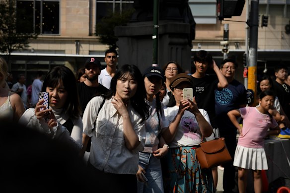  Along the route, shoppers stop to film the procession. 
