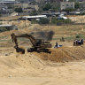 A backhoe removes sand barriers to create a buffer zone near entrances to tunnels in Rafah, along the Egyptian border.