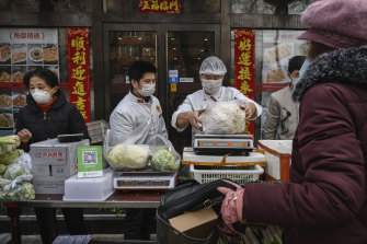 Chinese vendors wear protective masks as they sell vegetables in the street during the Chinese New Year holiday on Sunday in Beijing.