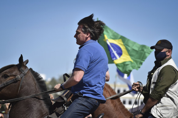 Brazilian President Jair Bolsonaro, on horseback, greets supporters outside the presidential palace in Brasilia on Sunday.
