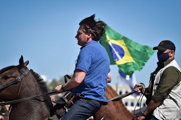 Brazilian President Jair Bolsonaro, on horseback, greets supporters outside the presidential palace in Brasilia on Sunday.