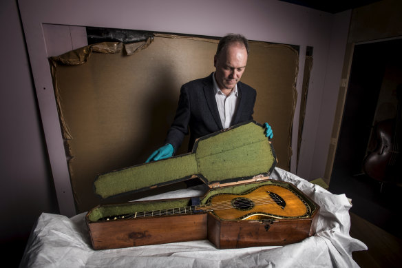 Dr Matthew Stephens removes the guitar, which is made of a satin wood veneer inlaid with ivory and mother of pearl, from its case as the show is installed.