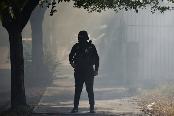 A police officer stands guard on a street surrounded by smoke in Colima, Mexico.