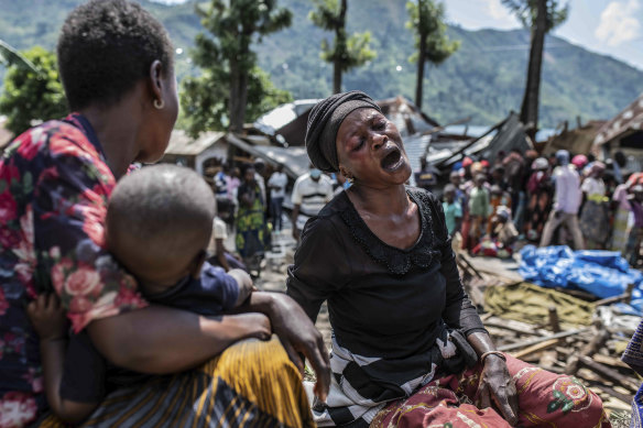 A woman reacts upon discovering that members of her family were killed, as volunteers nearby remove their bodies, in the village of Nyamukubi, South Kivu.