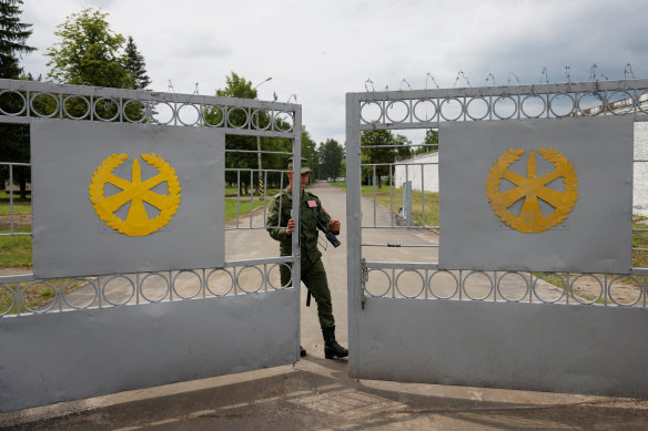 A Belarusian service member closes the gates of a disused base housing a tent camp set up for Wagner but unoccupied.