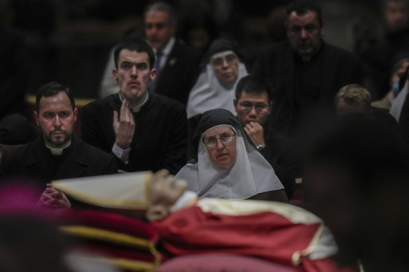 Mourners queue to see the body of late pope emeritus Benedict XVI, his head resting on a pair of crimson pillows.